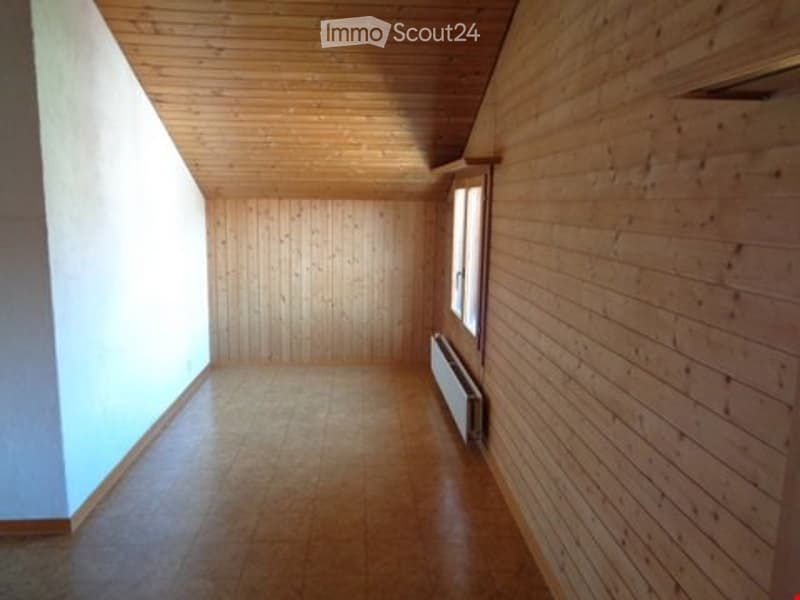Completely empty room with wooden walls, wooden ceiling, tiled floor, and a single window with white frame. No furniture or equipment.