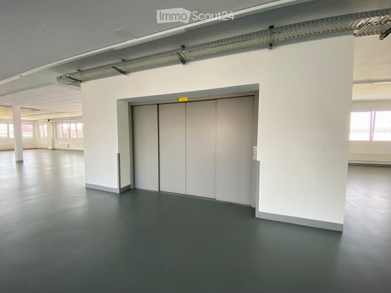 Empty room with white walls, grey floor, and a large white door. No furniture or equipment visible.