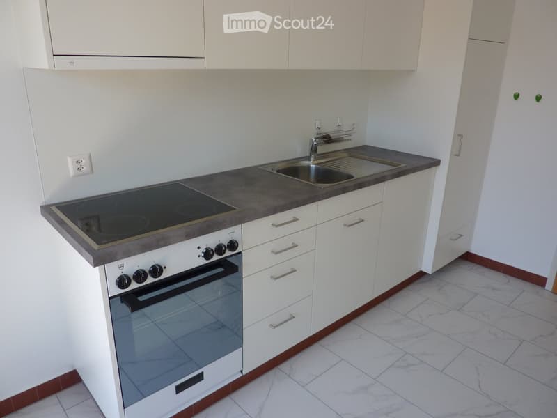 modern kitchen with electric stove, oven, sink, cabinets, and white marble flooring