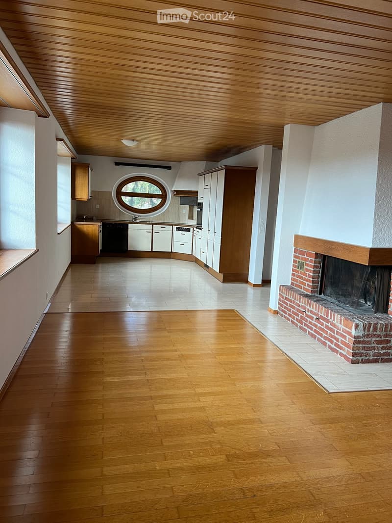 Open-plan living and dining area with wooden flooring, fireplace, and integrated kitchen featuring cabinets, a dishwasher, and a sink.