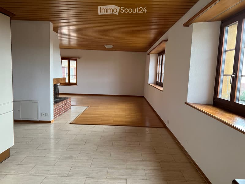 Empty room with wooden flooring, white walls, large windows, and a brick fireplace. No furniture or equipment present.