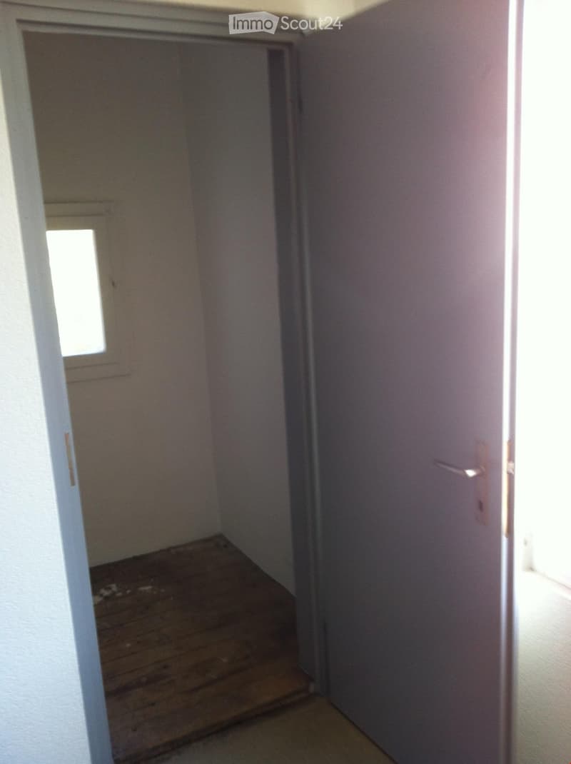 an empty room with a window and wooden floor