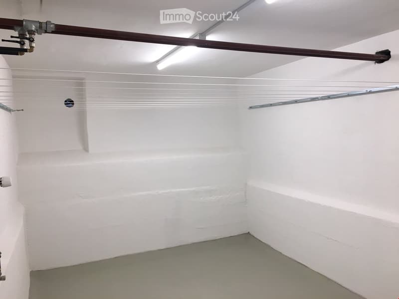 empty room, white walls, grey floor, laundry drying rack, white ceiling