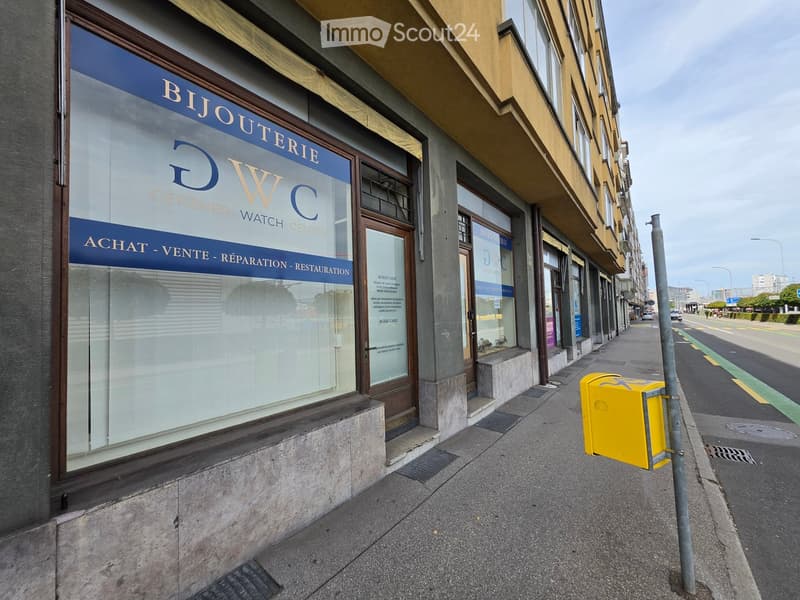 A storefront with a sign reading "BIJOUTERIE DWC" and additional text indicating services such as purchase, sale, repair, and restoration. The building has large glass windows and a wooden door.