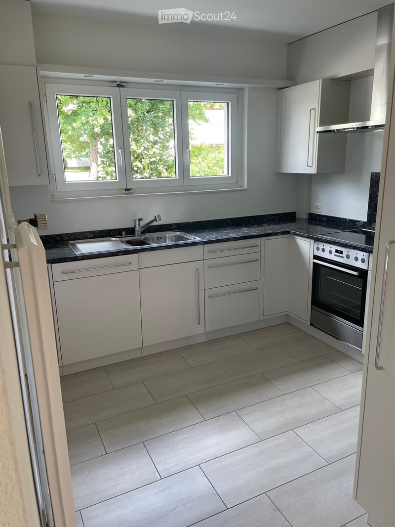 Modern kitchen with white cabinets, stainless steel appliances, granite countertops, and tiled flooring. Features a sink, faucet, and oven.