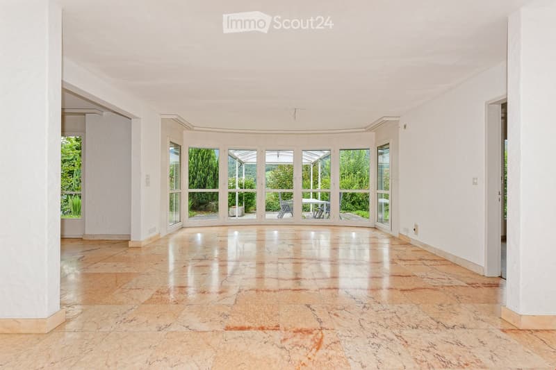 Bright, empty room with large glass doors leading to an outdoor area, polished tile floor, white walls, and minimal furnishings.