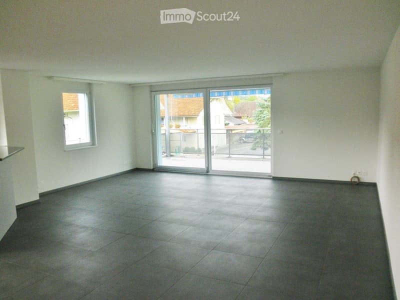 Empty room with tiled floor, light-colored walls, and large sliding glass doors leading to a balcony area.