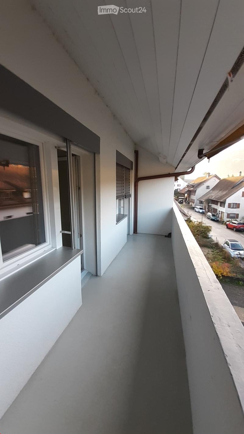 Concrete flooring, white walls, gray concrete windowsill, gray railing, large window