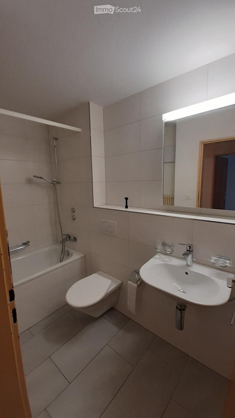 white tiles, white sink, white toilet, white bathtub, white toilet roll holder, large mirror, silver showerhead