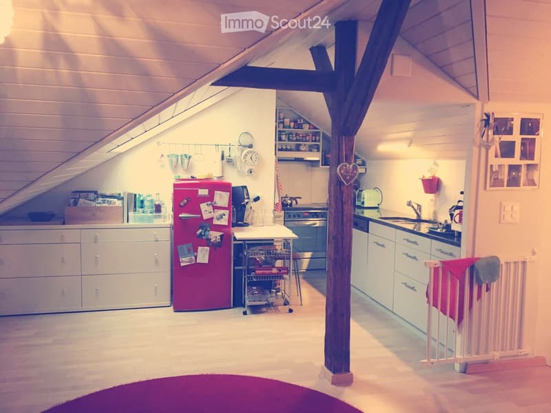Bright, compact kitchen with white cabinets, a red refrigerator, a central island, and modern appliances. Features include a sink, oven, and various kitchen utensils.
