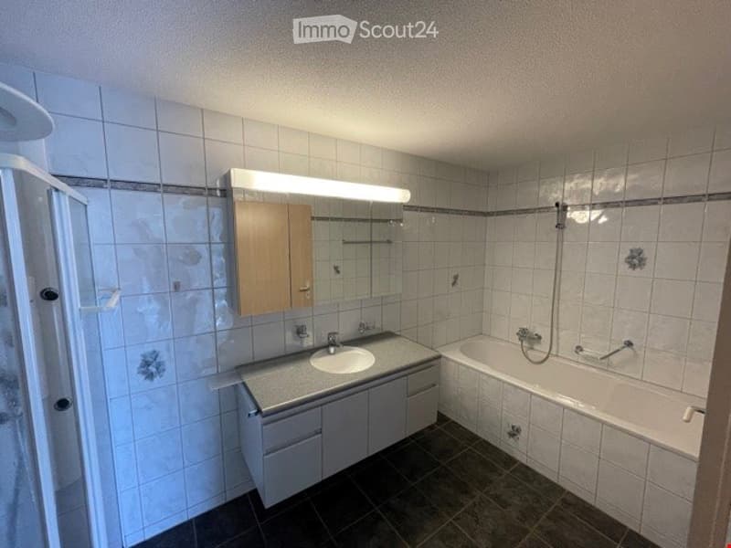 Modern bathroom with white tiled walls, a sink with a mirror, a bathtub, and a cabinet under the sink.