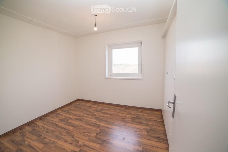 Empty room with wooden flooring, white walls, and a single window with white frame. No furniture or equipment present.