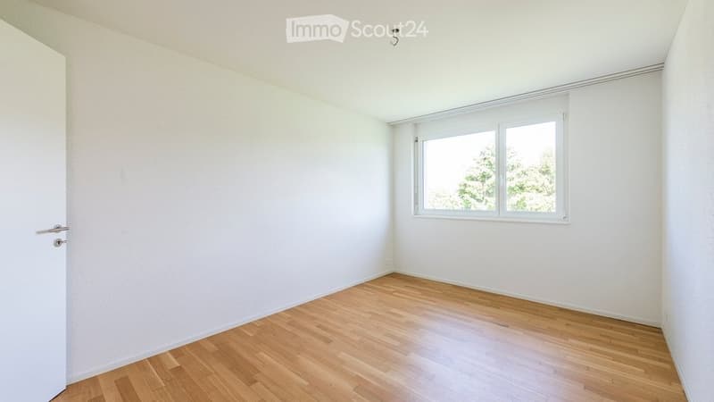 Empty room with white walls, wooden floor, and a window with white frame. No furniture or equipment visible.