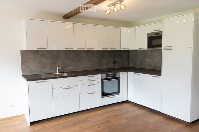Modern kitchen with white cabinets, stainless steel appliances, and a dark countertop.