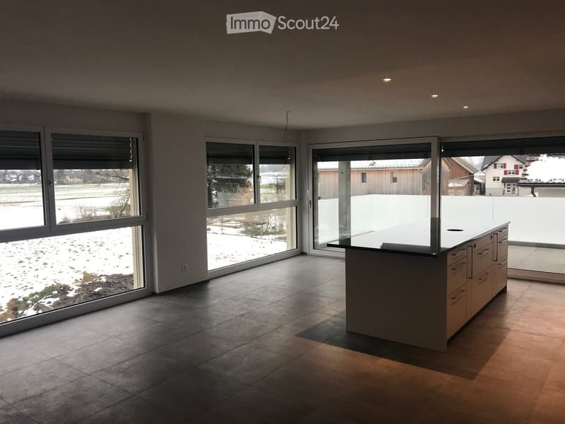 Modern kitchen with large windows, tiled floor, and a central kitchen island.