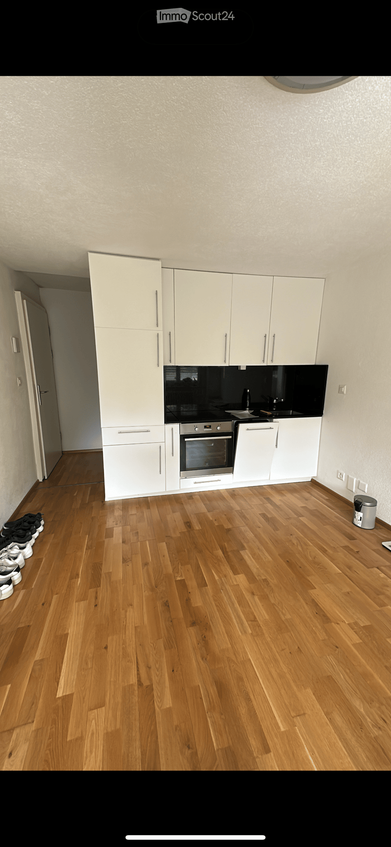 Modern kitchen with white cabinets, stainless steel oven, and wooden flooring.