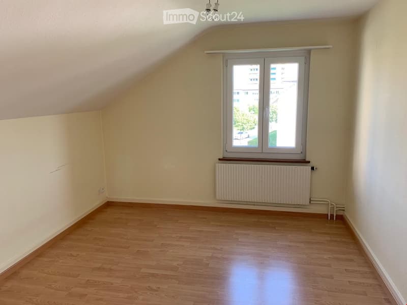 Empty room with wooden flooring, white walls, a window with blinds, and a radiator below the window.