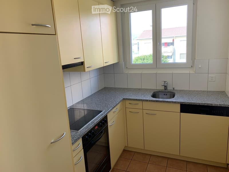 Modern kitchen with light-colored cabinets, granite countertop, sink, oven, and dishwasher.