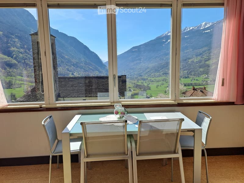 Dining room with a table and chairs, large windows with a view of mountains and a valley