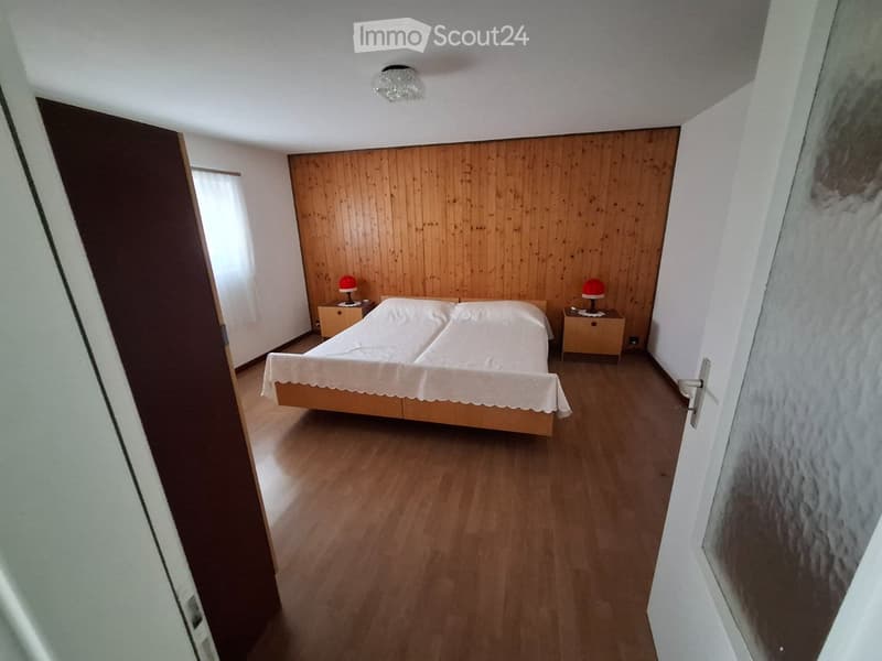 Bedroom with wooden walls, wooden floor, double bed, two nightstands with lamps, ceiling lamp