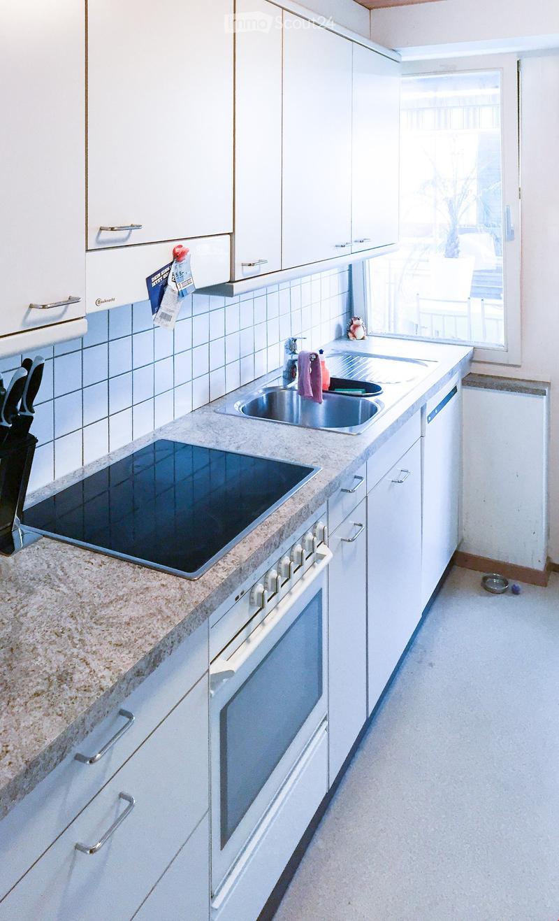 Modern kitchen with white cabinets, granite countertop, stainless steel sink, oven, and stove. Features a window with a view of the balcony.