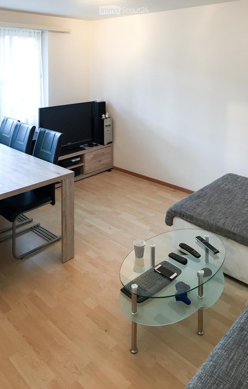 Living room with a sofa, coffee table, glass coffee table, chairs, TV stand, and a table with a keyboard and cellphone.
