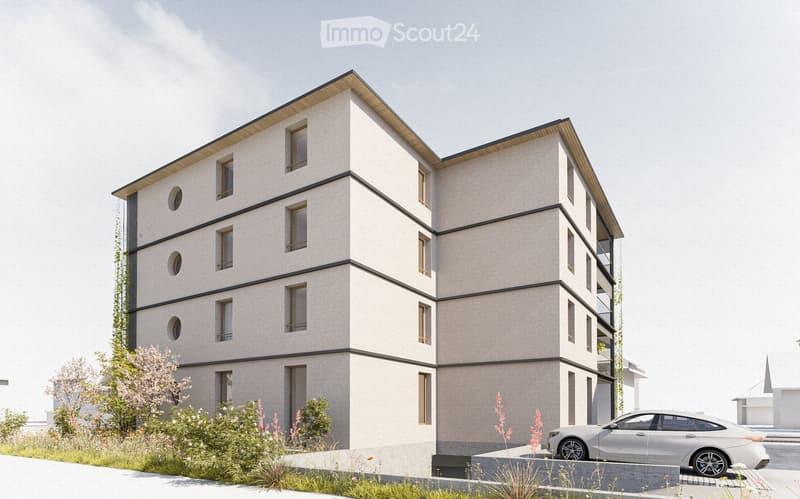 Modern multi-story building with a clean, contemporary design, featuring large windows and a flat roof. The building has a light-colored facade with dark accents and is surrounded by a landscaped area with small plants and a parked car.