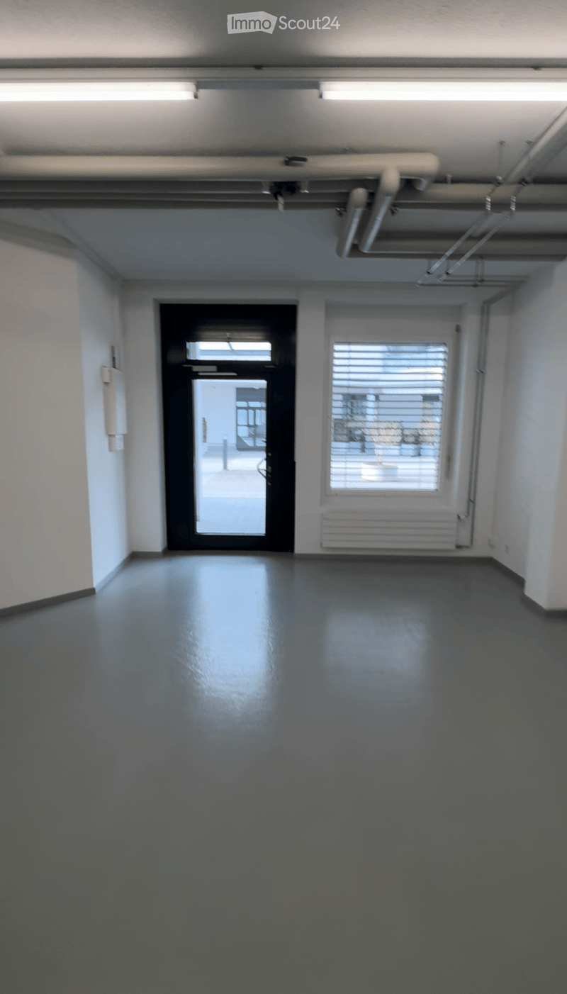 Empty room with dark blue walls and floor, featuring a large window with blinds and a door leading outside.