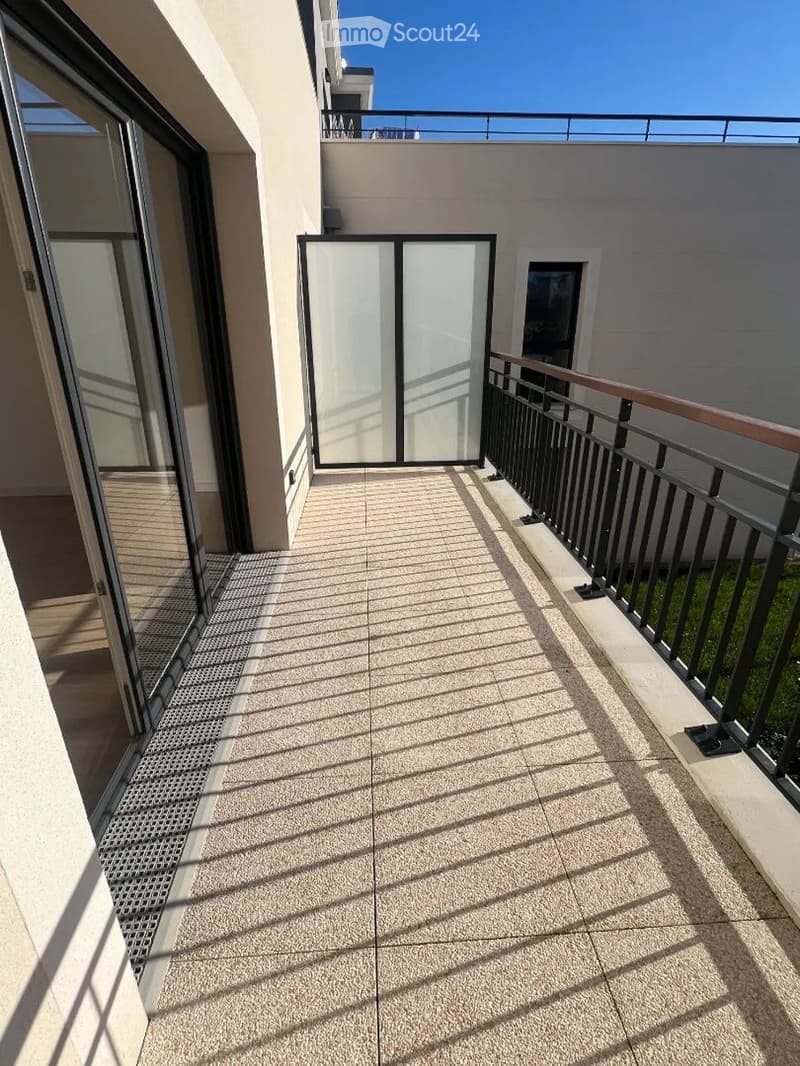 Balcony with tiled floor, metal railing, and sliding glass doors leading to the interior.