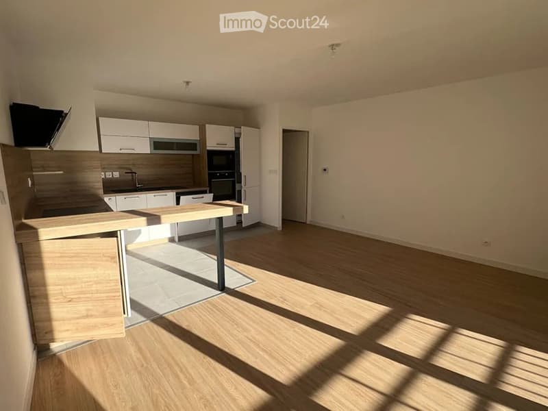 Modern kitchen with white cabinets, stainless steel appliances, and a wooden island. The space is bright with natural light and features a clean, contemporary design.