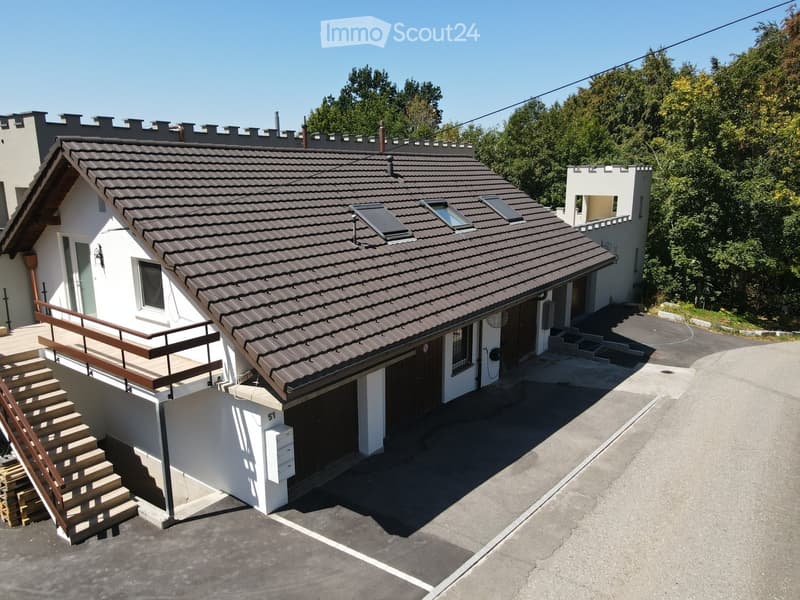 Two-story house with a tiled roof, white exterior, garage, and small balcony with wooden stairs.
