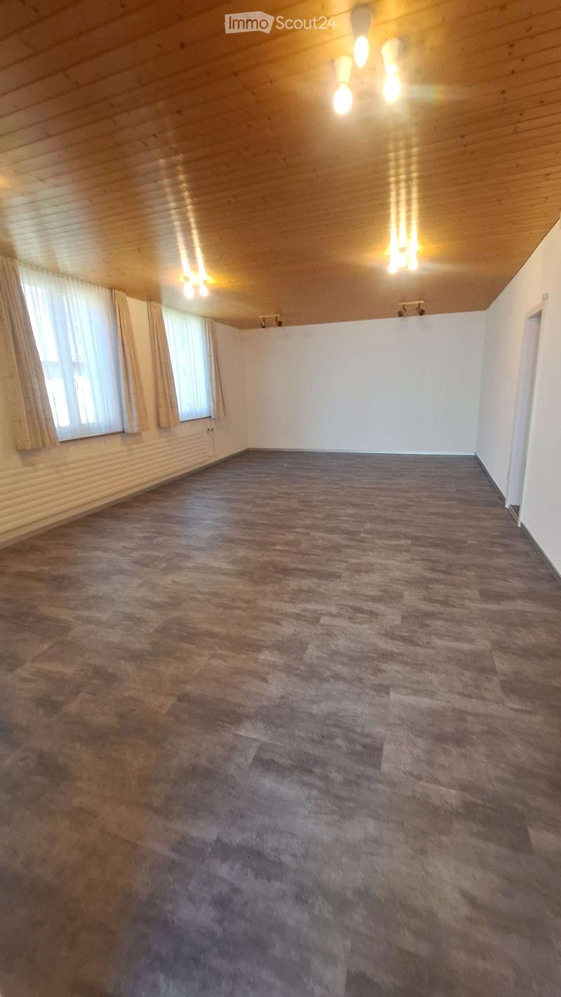 Empty room with wooden ceiling, carpeted floor, large windows with curtains, and recessed lighting.