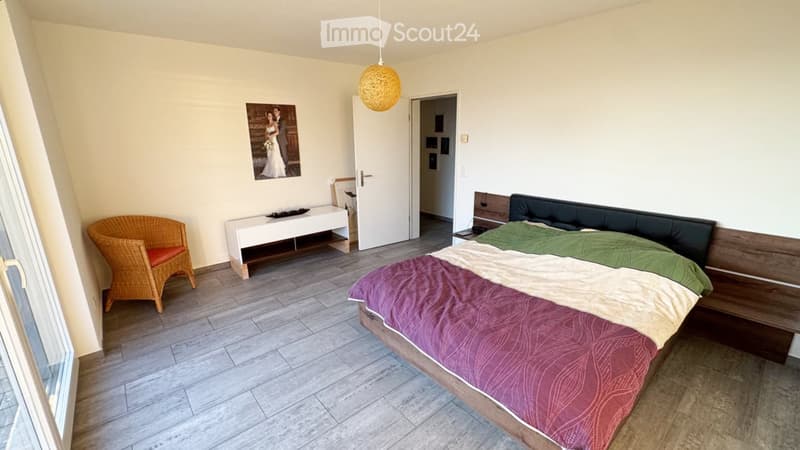 Bedroom with a double bed, a wicker chair, a small table, and a picture frame on the wall.