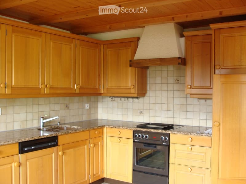 A well-lit kitchen with wooden cabinets, granite countertops, a stainless steel sink, and a built-in oven and dishwasher.