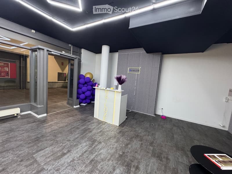 Modern reception area with a reception desk, balloon cluster, vase, and a small table with chairs.