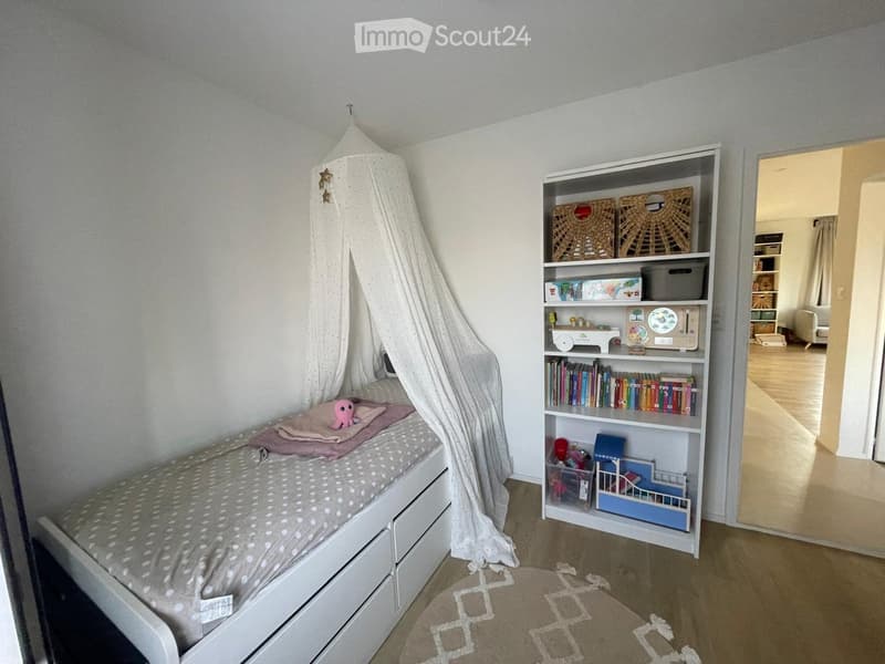 Cozy children's bedroom with a single bed, bookshelf, and a small rug on the floor.