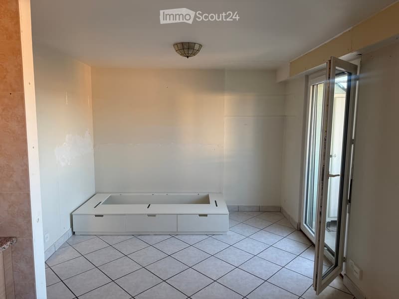Bathroom with a white bathtub, tiled floor, and a large window with a sliding door.