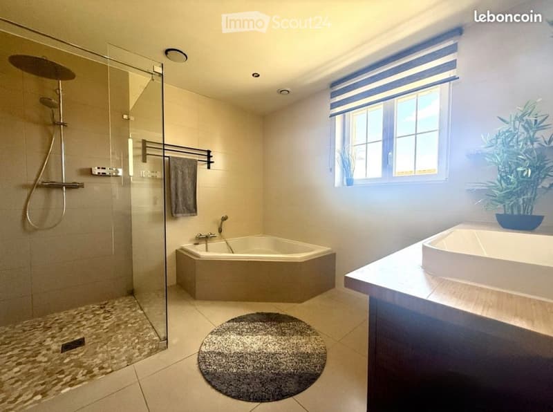 Modern bathroom with a corner bathtub, glass-enclosed shower, towel rack, and a small plant on the windowsill.