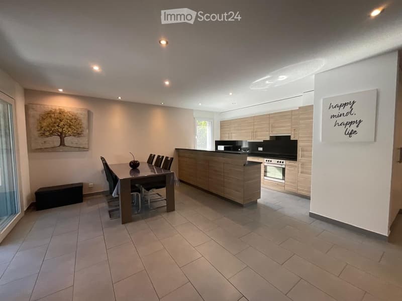 Open-plan kitchen and dining area with modern wooden cabinets, a central island, a dining table with chairs, and a bench along the wall.