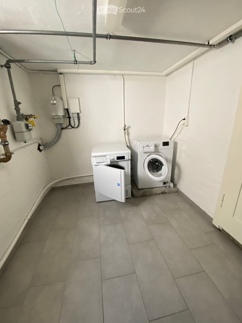 Small utility room with tiled floor, white walls, and two white appliances: a washing machine and a dishwasher.