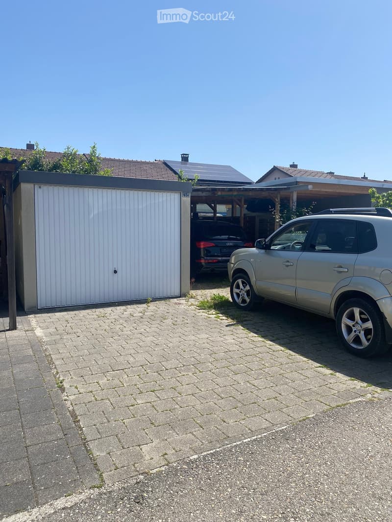 Driveway with a parked SUV, garage, and neighboring houses with solar panels on the roof.