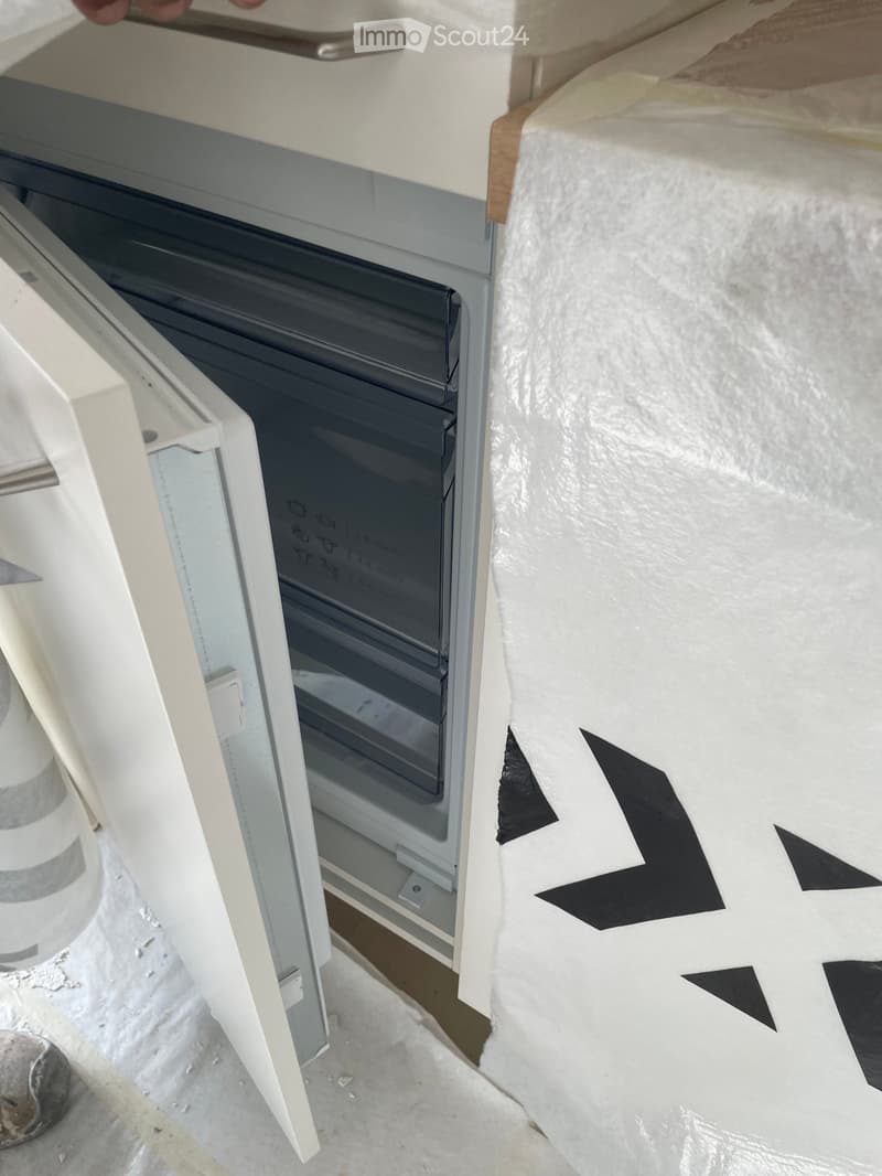 A modern bathtub with a sleek, white frame and a black interior, positioned against a wall covered in protective plastic sheeting.