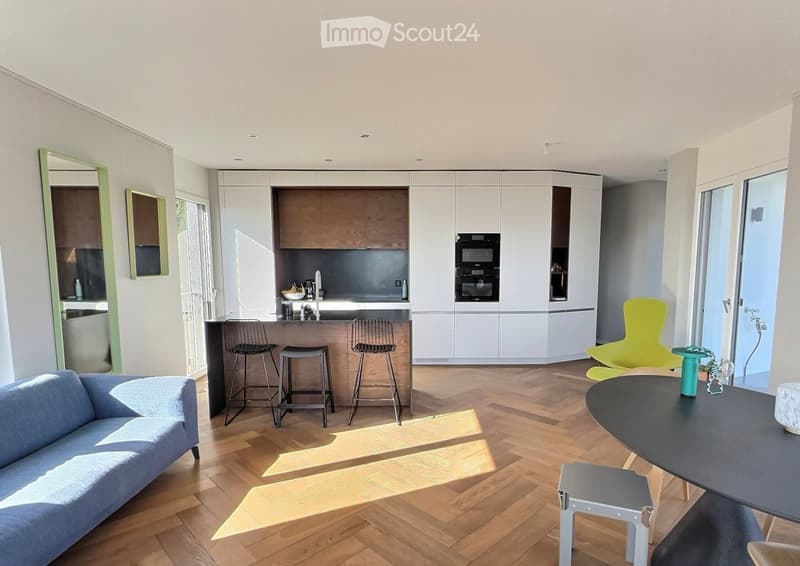 Modern open-plan living and dining area with a blue sofa, black dining table, yellow chair, and kitchen area with cabinets and appliances.