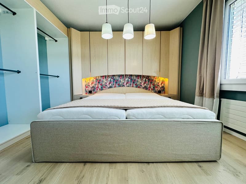 Modern bedroom with a large double bed, built-in wardrobe, pendant lights, and a floral headboard accent wall.