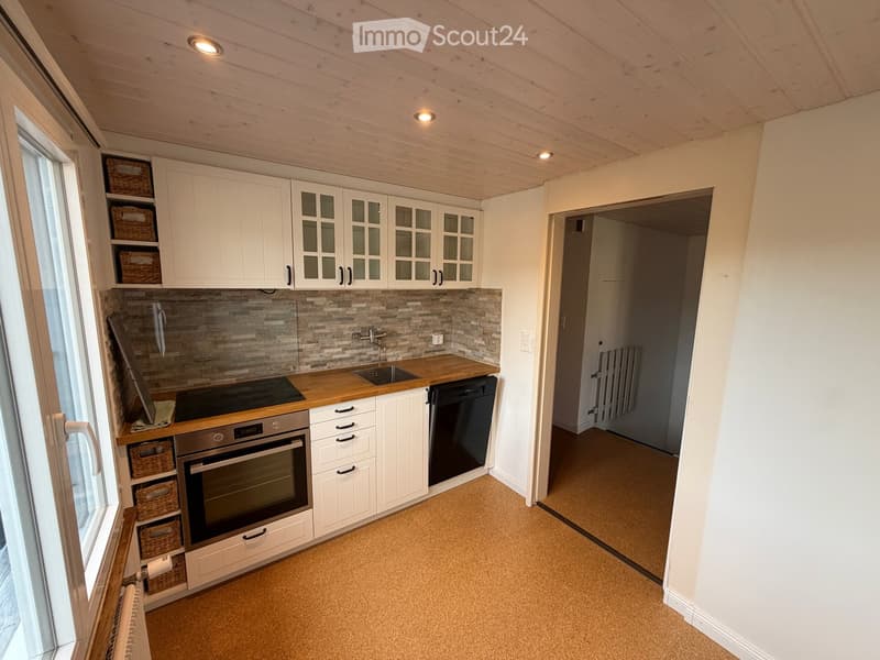 Modern kitchen with white cabinets, wooden countertops, stainless steel appliances, and a tiled backsplash. Features an oven, dishwasher, sink, and wicker baskets on the cabinet.