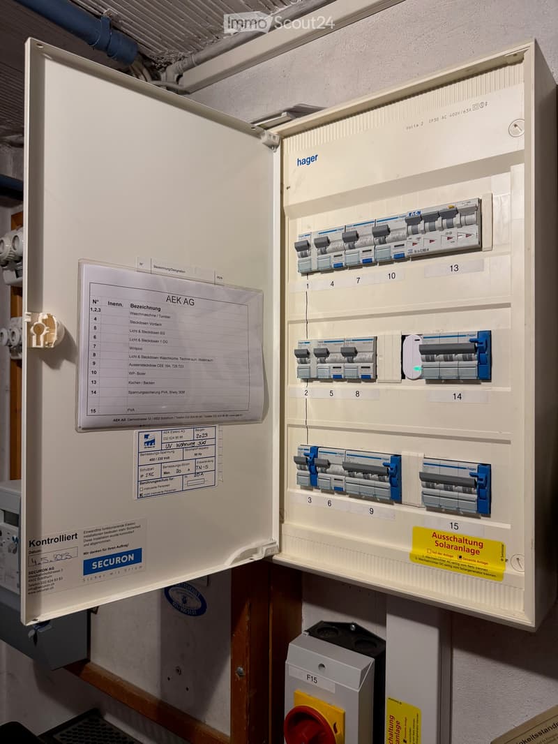 An open electrical circuit breaker panel with multiple switches and a label sheet attached to the left side.