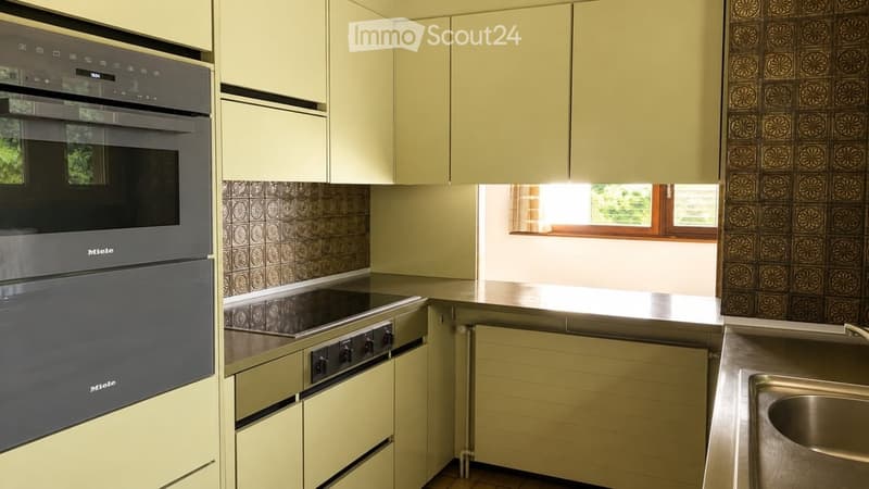Modern kitchen with light-colored cabinets, stainless steel appliances, and a window providing natural light.