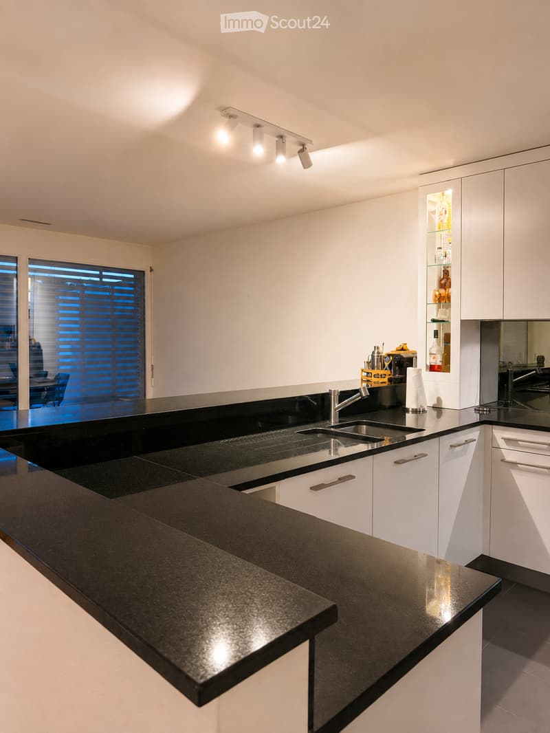 Modern kitchen with white cabinets, black countertops, and stainless steel sink.