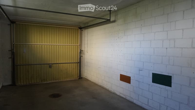 Empty garage with white brick walls, a metal garage door, and a concrete floor.