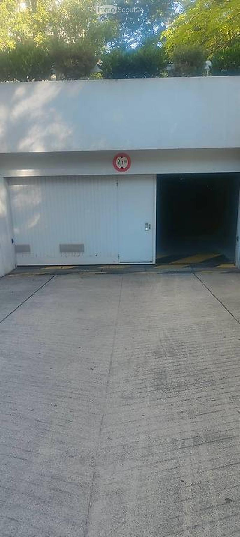 A modern, white garage with two large doors, one open, and a speed limit sign above it.